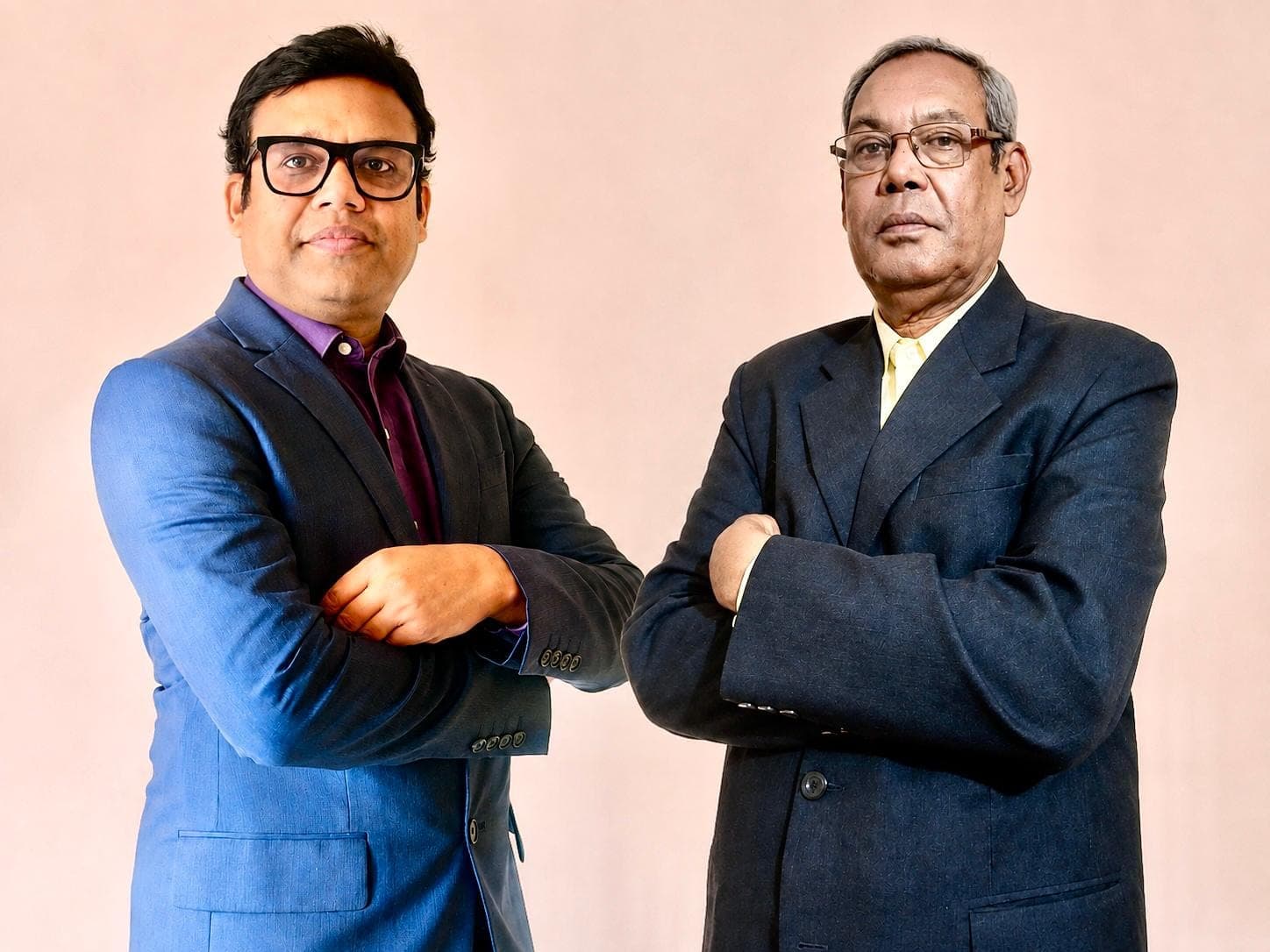 Two men in suits standing side by side with their arms folded